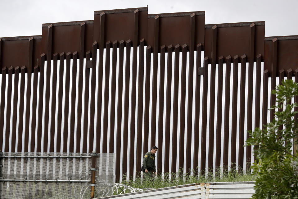 FILE - In this March 18, 2020, file photo, a Border Patrol agent walks along a border wall separating Tijuana, Mexico, from San Diego, in San Diego. Vice President Mike Pence in March directed the nation’s top disease control agency to use its emergency powers to effectively seal the U.S. borders, overruling the agency’s scientists who said there was no evidence the action would slow the coronavirus, according to two former health officials. (AP Photo/Gregory Bull, File)