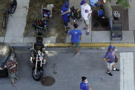 Chicago Cubs fans wait for a ball outside of Wrigley Field before the Opening Day baseball game between the Chicago Cubs and the Milwaukee Brewers in Chicago, Friday, July 24, 2020, in Chicago. In a normal year, that would mean a sellout crowd at Wrigley Field and jammed bars surrounding the famed ballpark. But in a pandemic-shortened season, it figures to be a different atmosphere. (AP Photo/Nam Y. Huh)