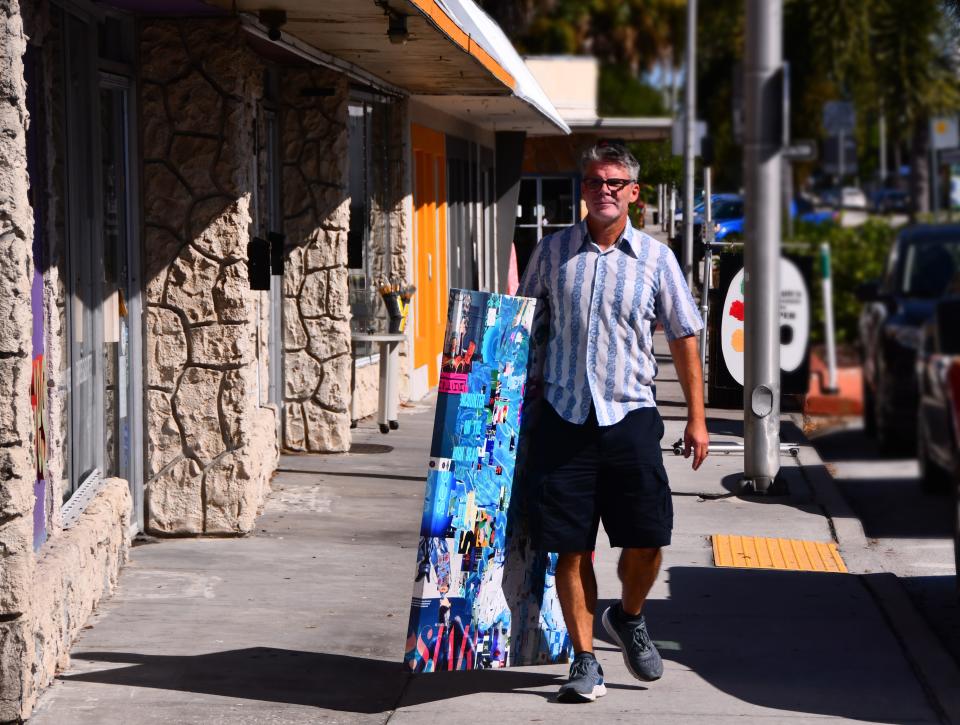 Derek Gores carries a canvas of collage artwork under his arm while he walks past his future building along the Highland Avenue sidewalk.