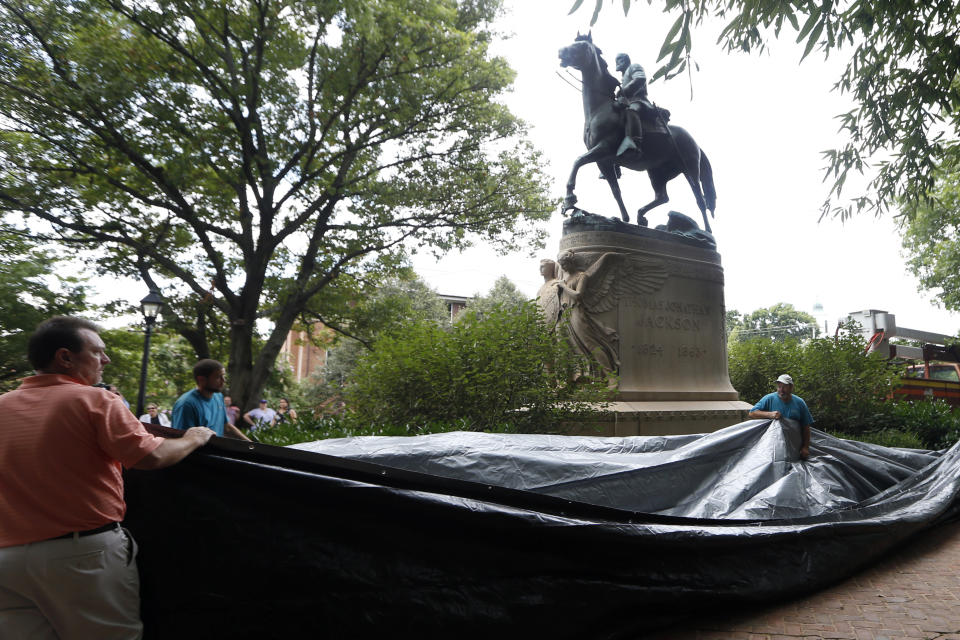 FILE - In this Aug. 23, 2017, file photo, city workers prepare to drape a tarp over the statue of Confederate Gen. Stonewall Jackson in Court Square Park, formerly Justice Park, in Charlottesville, Va. Charlottesville officials have voted unanimously to remove two statues of Confederate generals Robert E. Lee and Stonewall Jackson from two downtown parks including one that was the focus of a violent white nationalist rally in 2017. News outlets report that the vote came late Monday, June 7, 2021, after more than 50 people spoke during a virtual meeting, most in favor of removal. (AP Photo/Steve Helber, File)