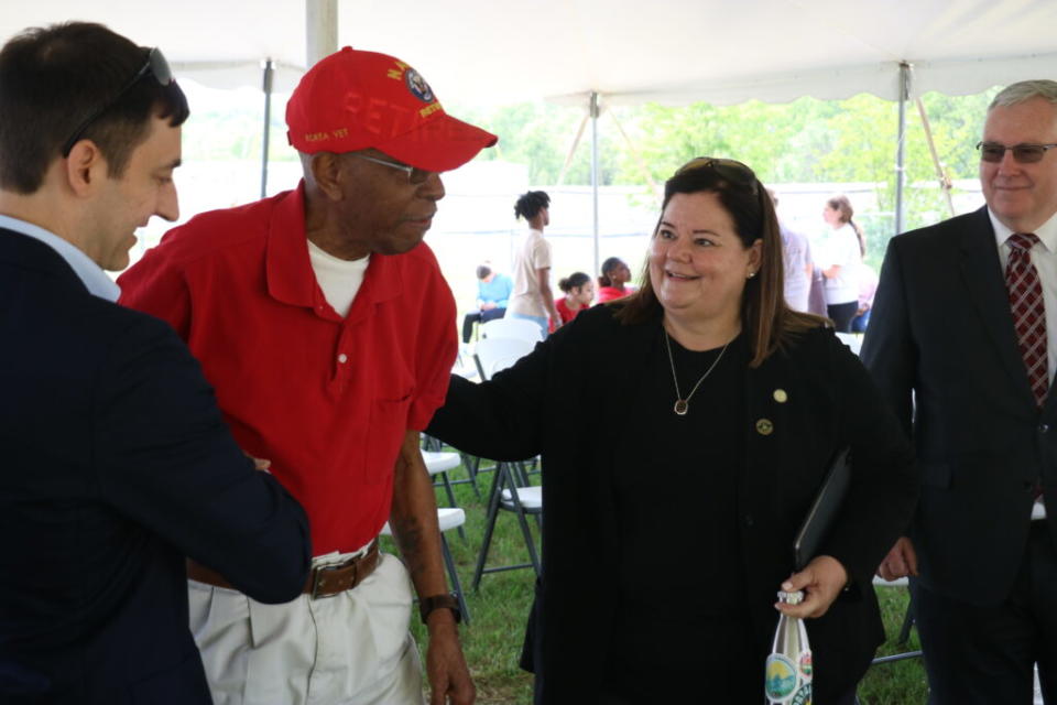 Jeaneanne Gettle, wearing a black shirt, helps David Downey, wearing a red shirt and red hat, out of his chair.