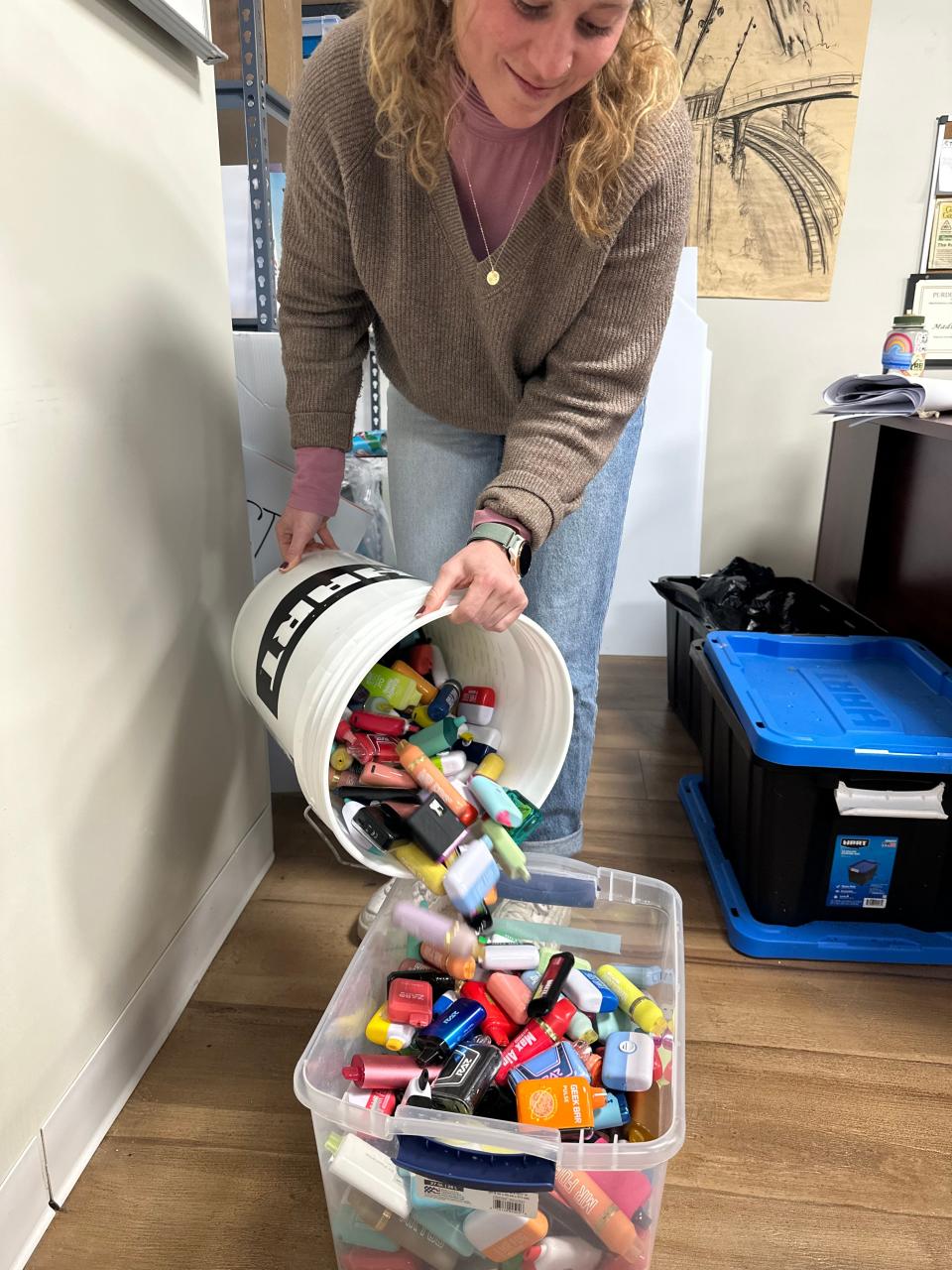 Madison Neher pours a load of disposable vapes into a large tote, all to be recycled through an Indianapolis-based program.