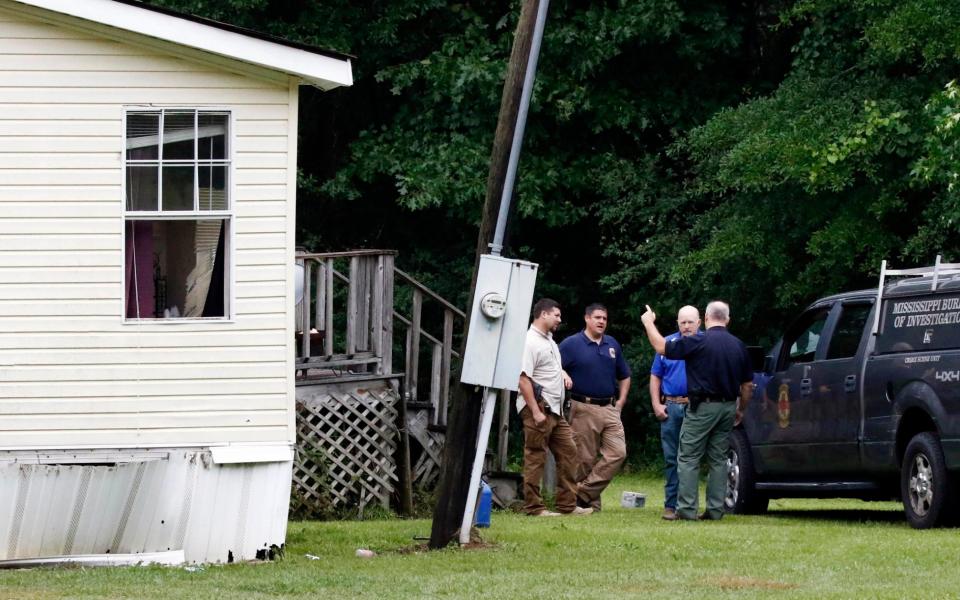 Investigators stand outside a Bogue Chitto house, where several people were killed - Credit: AP