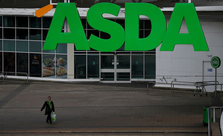 FILE PHOTO: An ASDA employee walks beneath a company logo outside a store in Manchester, northern England, July 8 , 2016. REUTERS/Phil Noble