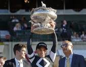 FILE - Jockey Joel Rosario, center, holds up the August Belmont Trophy after winning the 151st running of the Belmont Stakes horse race, Saturday, June 8, 2019, in Elmont, N.Y. Triple Crown winner Justify, 2017 Horse of the Year Gun Runner and jockey Joel Rosario have been elected to the National Museum of Racing and Hall of Fame in their first year of eligibility. (AP Photo/Eduardo Munoz Alvarez, File)