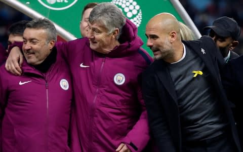  Manchester City's manager Pep Guardiola, right, wears a yellow ribbon during the celebrations after his side won the English League Cup Final between Arsenal and Manchester City - Credit: AP