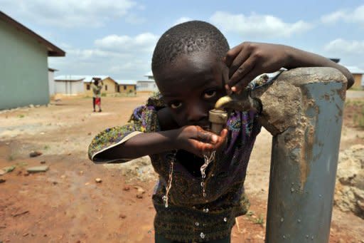 A boy drinks from a water tap in a 'new town' built by the diamond mining company Koidu Holdings, which aims to provide access to clean drinking water, education and training, free healthcare and infrastructure, in Koidu, the capital of the diamond-rich Kono district, in eastern Sierra Leone, some 250 km east from Freetown, in April