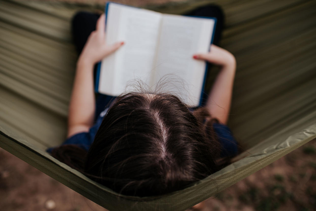 Center overhead frame of teen girl reading in hammock