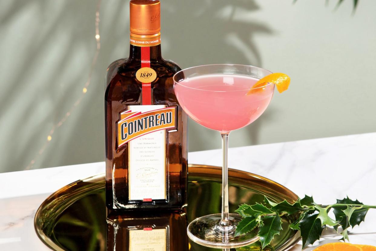 bottle of Cointreau and glass with pink cocktail on brass tray