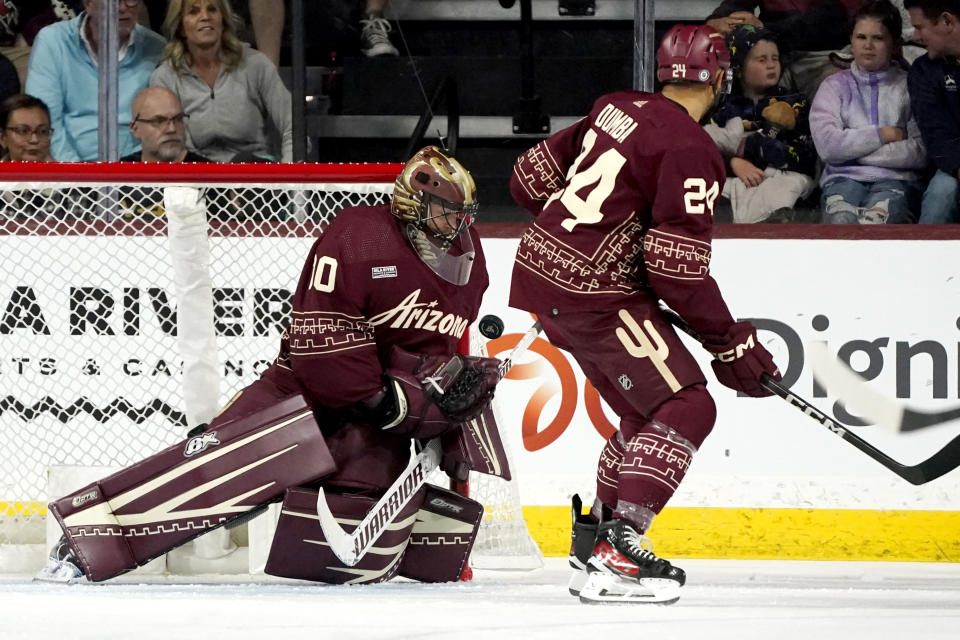 Arizona Coyotes goaltender Karel Vejmelka, left, makes a save against the Winnipeg Jets as Coyotes defenseman Matt Dumba (24) looks on during the first period of an NHL hockey game Saturday, Nov. 4, 2023, in Tempe, Ariz. (AP Photo/Ross D. Franklin)