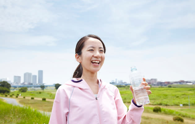 Happy looking asian woman holding bottle of water. (Getty Images)