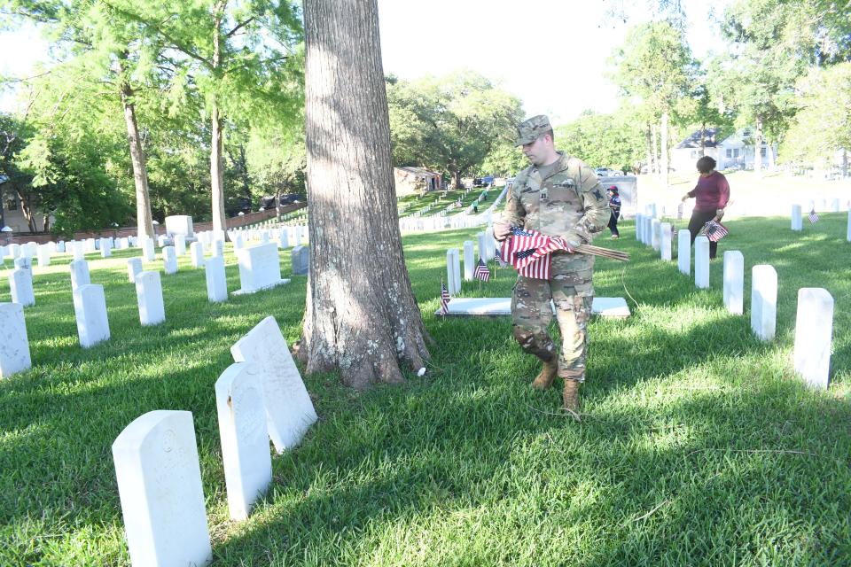 National Guard Chaplin Travis Milner and several others from Christus Hospice St. Frances Cabrini Hospital, place flags on gravesites in preparation for the Memorial Day program set for Monday.