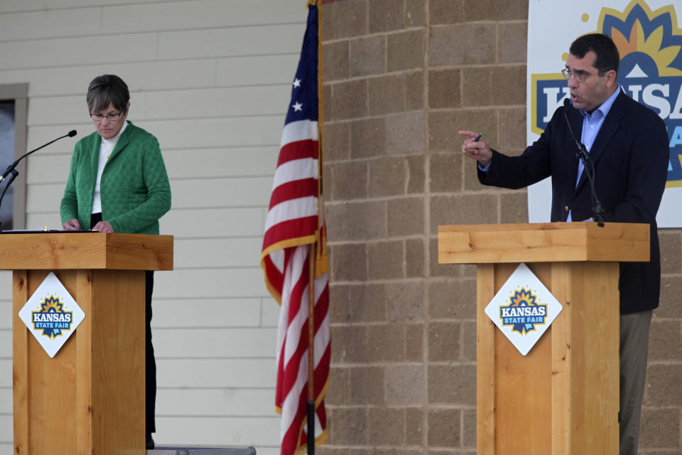 Kansas Attorney General Derek Schmidt, right, the Republican nominee for governor, makes a point during a debate as Democratic Gov. Laura Kelly watches at the Kansas State Fair, Saturday, Sept. 10, 2022, in Hutchinson, Kan. Both candidates are appealing to independents and moderate Republicans, who are crucial swing voters. (AP Photo/John Hanna)