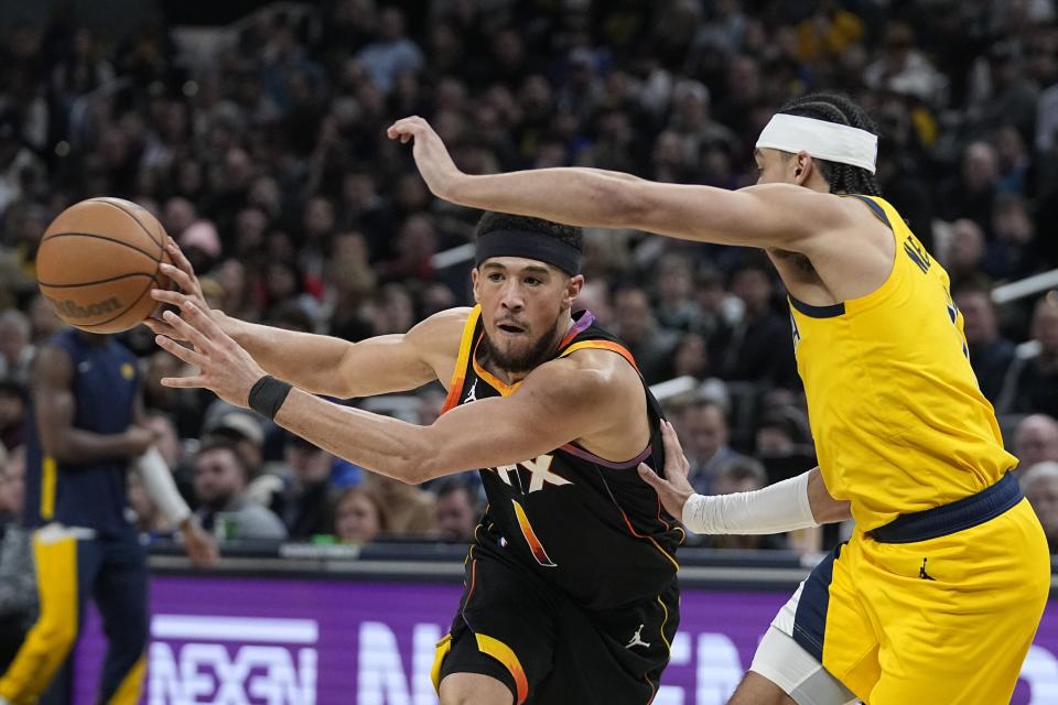 Phoenix Suns' Devin Booker (1) passes the ball away from Indiana Pacers' Andrew Nembhard (2) during the first half of an NBA basketball game Friday, Jan. 26, 2024, in Indianapolis. (AP Photo/Darron Cummings)