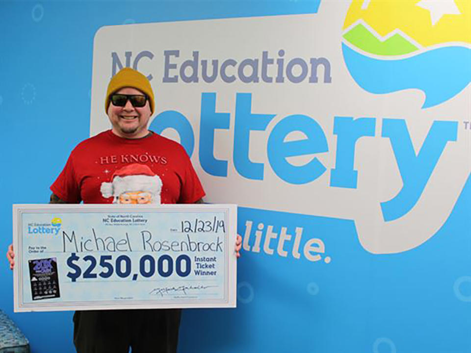 This Monday, Dec. 23, 2019 photo provided by N.C. Education Lottery shows Michael Rosenbrock of Mint Hill, N.C. holding an oversized check after winning $250,000 from a lottery ticket in Raleigh. Rosenbrock won after stopping by a grocery store to buy some last-minute fixings for Christmas dinner. North Carolina lottery officials said in a statement that Rosenbrock claimed his prize on Monday.  (N.C. Education Lottery via AP)