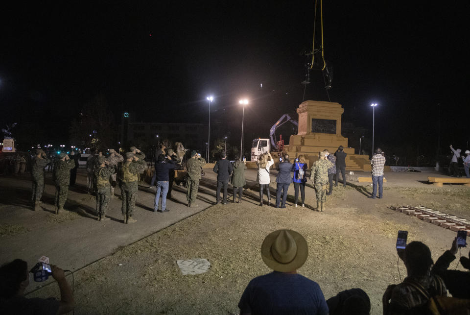 Soldiers salute as they stand guard while a statue of General Manuel Baquedano, a Chilean military officer and politician, is removed for restoration from Plaza Italia in Santiago, Chile, Friday, March 12, 2021. The statue located at the epicenter of the protests in Chile was removed for restoration with an order by the National Monuments Council. (AP Photo/Esteban Felix)