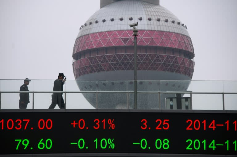 People wake on a bridge with a board showing the numbers of worlds stock exchange rates in the Lujiazui Financial District of Shanghai on November 25, 2014