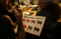 In this March 20, 2017 photo people order beef during dinner at a restaurant while taking part of an activity called "The Argentine Experience" in Buenos Aires, Argentina. Tourists participating in "The Argentine Experience" have the chance to learn about the local cuisine, wine and traditions during a dinner in Buenos Aires. (AP Photo/Natacha Pisarenko)