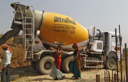 FILE PHOTO: Workers walk in front of an UltraTech concrete mixture truck at the construction site of a commercial complex on the outskirts of the western Indian city of Ahmedabad April 22, 2013. REUTERS/Amit Dave