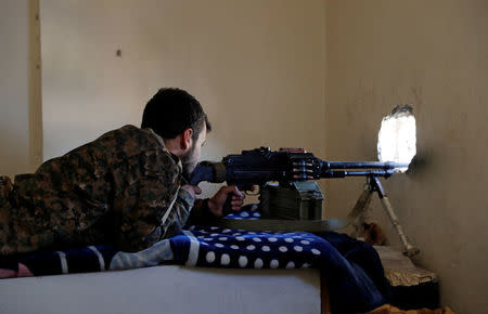 A fighter of Syrian Democratic Forces aims a machine gun towards the positions of the Islamic State militants holed up in the National Hotel complex at the frontline in Raqqa, Syria October 16, 2017. REUTERS/Erik De Castro