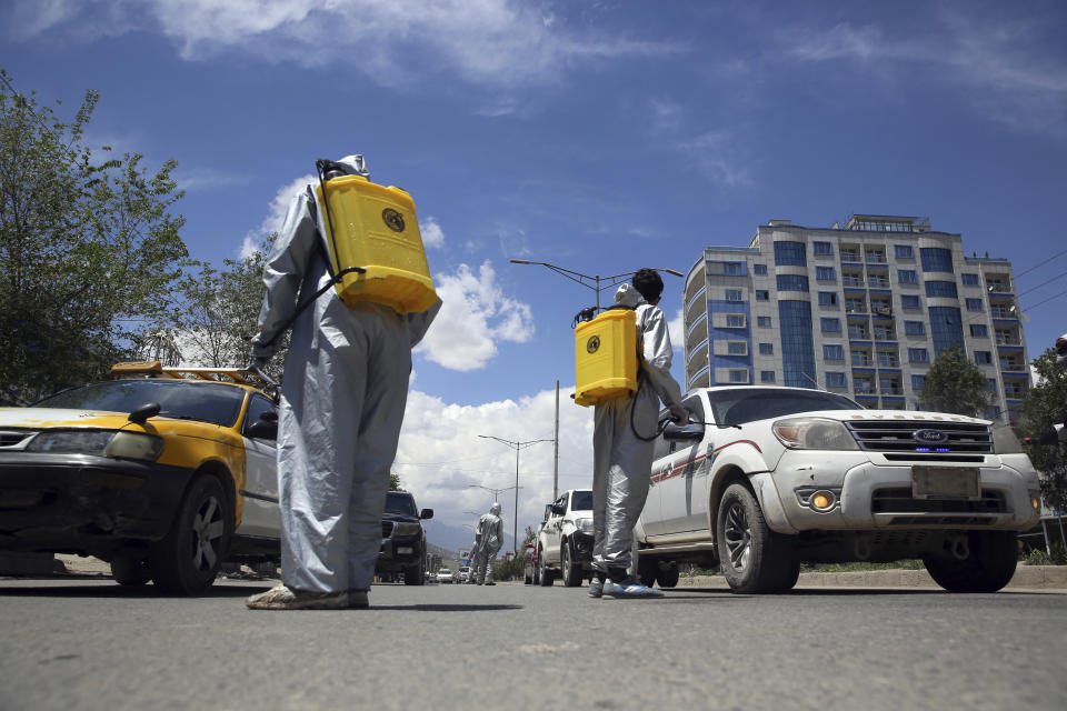 Volunteers in protective suits spray disinfectant on passing vehicles to help curb the spread of the coronavirus in Kabul, Afghanistan, Sunday, May 3, 2020. (AP Photo/Rahmat Gul)