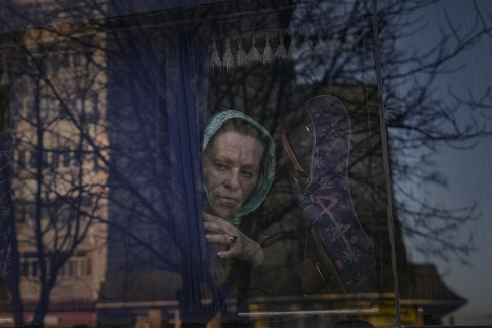 A woman waits on a bus for Ukrainian police to check papers and belongings in Brovary, Ukraine, Sunday, March 20, 2022, after 1600 people of which 843 children, according to authorities, were evacuated from the village of Bobrik, reportedly under Russian military control. Russian forces pushed deeper into Ukraine's besieged and battered port city of Mariupol on Saturday, where heavy fighting shut down a major steel plant and local authorities pleaded for more Western help. (AP Photo/Vadim Ghirda)