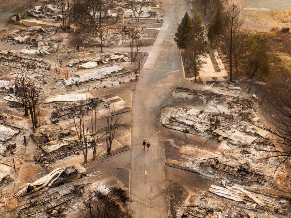 In this aerial view from a drone, people walk through a mobile home park destroyed by fire on 10 September in Phoenix, Oregon. Hundreds of homes in the town have been lost due to wildfire.