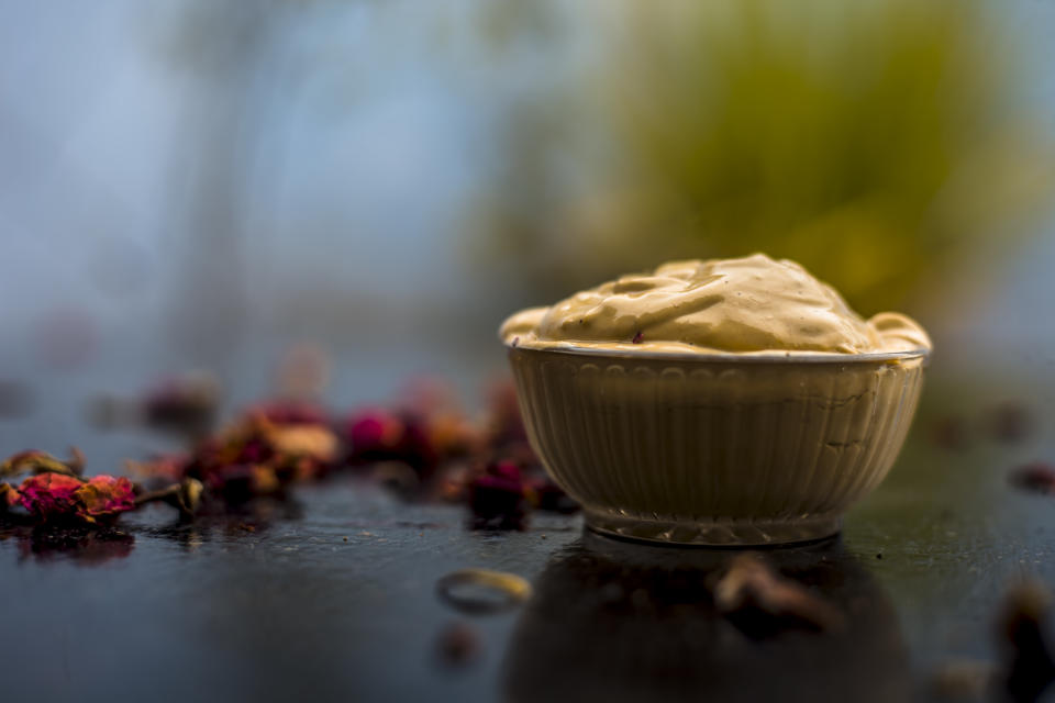 Ubtan/face mask/face pack of Multani mitti or fuller's earth on wooden surface in a glass bowl consisting of Multani mitti and rose water for the remedy or treatment of oily skin.On wooden surface.