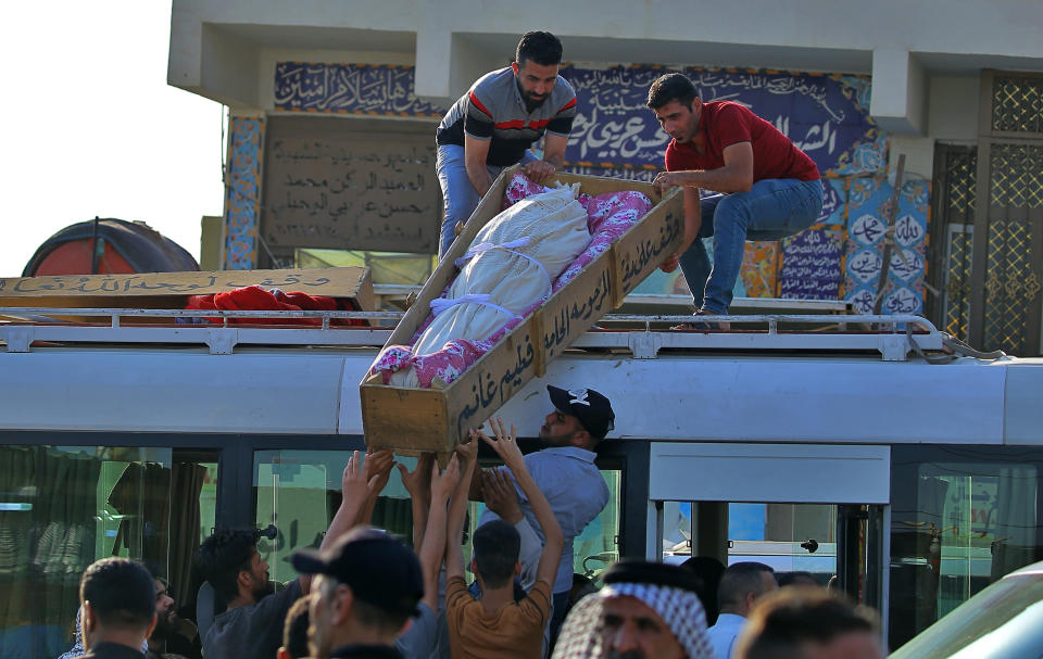 Mourners prepare to bury victims of a Monday bombing at a Baghdad market busy with shoppers a day before the Muslim Eid al-Adha holiday, in Najaf, Iraq, Tuesday, July 20, 2021. ​Iraqi medical officials said the Monday bomb attack in Sadr City, a Baghdad suburb, killed at least 30 people and wounded dozens of others. (AP Photo/Anmar Khalil)