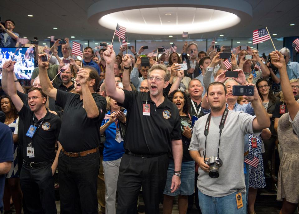 Jim Green, NASA Planetary Science Division director, center, and other New Horizons team members count down to the spacecraft's closest approach to Pluto, Tuesday, July 14, 2015 at the Johns Hopkins University Applied Physics Laboratory (APL) in Laurel, Maryland. The moment of closest approach for the New Horizons spacecraft came around 7:49 a.m. EDT Tuesday, culminating an epic journey from planet Earth that spanned an incredible 3 billion miles and 9Ω years.  (Bill Ingalls/NASA via AP)