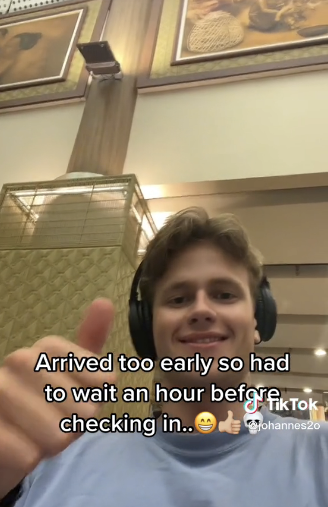 Man smiling and giving a thumbs-up with caption "Arrived too early so had to wait an hour before checking in" with big smile, thumbs-up, and skull emojis