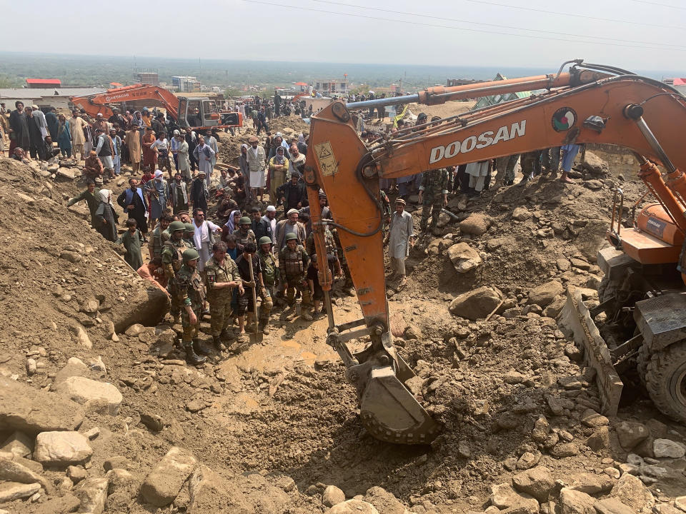 Soldiers and locals search for victims in a mudslide following heavy flooding in the Parwan province, north of Kabul, Afghanistan, Wednesday, Aug. 26, 2020. Heavy flooding in northern Afghanistan has killed and injured dozens of people officials said Wednesday. (AP Photo/Rahmat Gul)