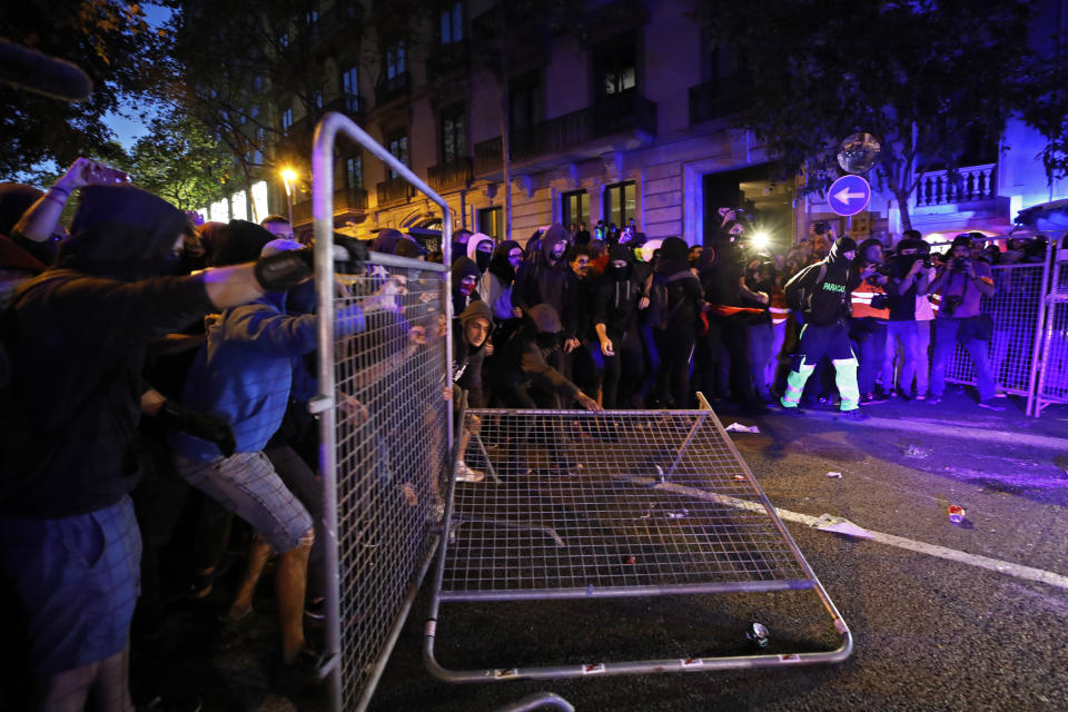 Protestors bring down a fence outside the Spanish Government Office in Barcelona, Spain, Tuesday, Oct. 15, 2019. Spain's Supreme Court on Monday convicted 12 former Catalan politicians and activists for their roles in a secession bid in 2017, a ruling that immediately inflamed independence supporters in the wealthy northeastern region. (AP Photo/Emilio Morenatti)