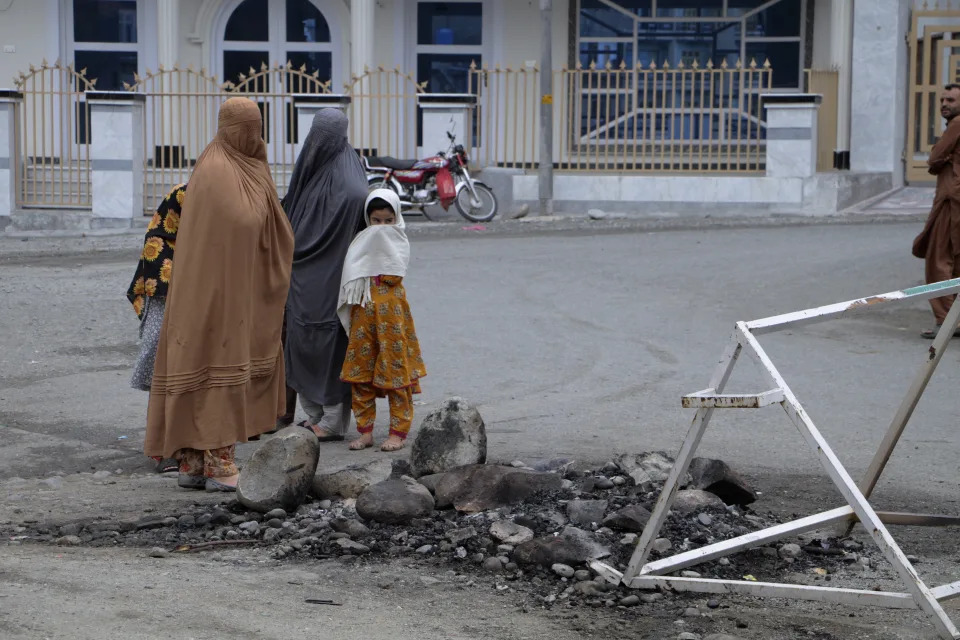 Women and children look at a spot where a Muslim mob lynched and burned a man over allegations that he had desecrated Islam's holy book, the Quran, in Madyan in Pakistan's Khyber Pakhtunkhwa province, Friday, June 21, 2024. The attackers also torched a police station which had held the man in Madyan and burned police vehicles parked there, according to local police official Rahim Ullah. (AP Photo/Naveed Ali)