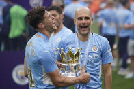 Manchester City's head coach Pep Guardiola, right, smiles with trophy after winning the 2022 English Premier League title at the Etihad Stadium in Manchester, England, Sunday, May 22, 2022. (AP Photo/Dave Thompson)