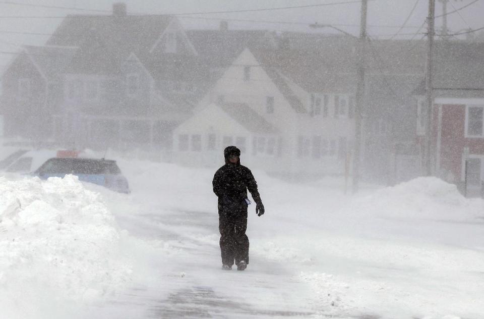 A passer-by walks through snow and strong wind along an empty street in Marshfield, Mass., Wednesday, Jan. 22, 2014. Temperatures across the state were in the single digits early Wednesday. (AP Photo/Steven Senne)