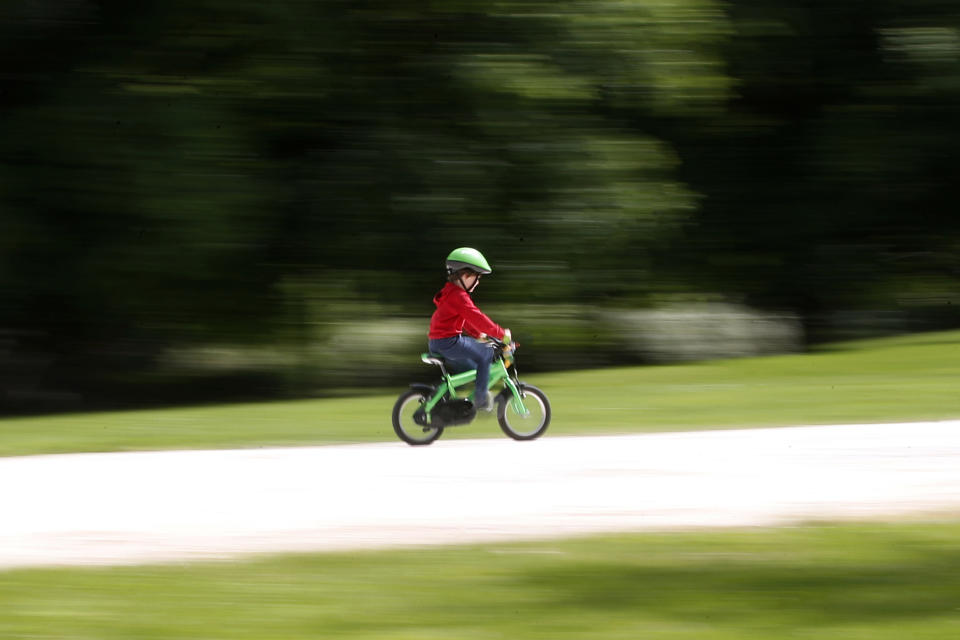 FILE - In this May 4, 2020 file photo, a child rides a bicycle in a park which reopened after several weeks of closure, due coronavirus lockdown restrictions, in Milan, Italy. A national survey of the psychological impact of coronavirus lockdowns on Italian children presented in Rome on Tuesday, June 16, 2020, has quantified what many parents noticed offhand during weeks cooped up at home: Their kids were more irritable, had trouble sleeping and for some of the youngest, wept inconsolably and regressed developmentally. (AP Photo/Antonio Calanni, fiel)