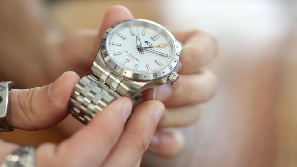 The Christopher Ward Consort bracelet in use on a C63 Sealander GMT, against a wooden background