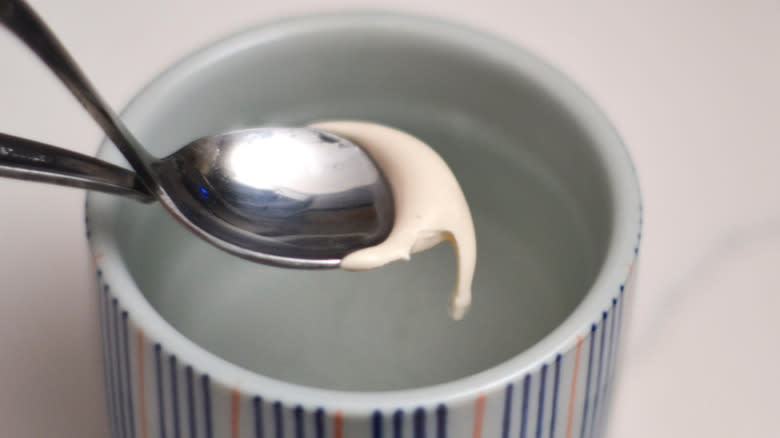 firm nougat in spoon over glass of water