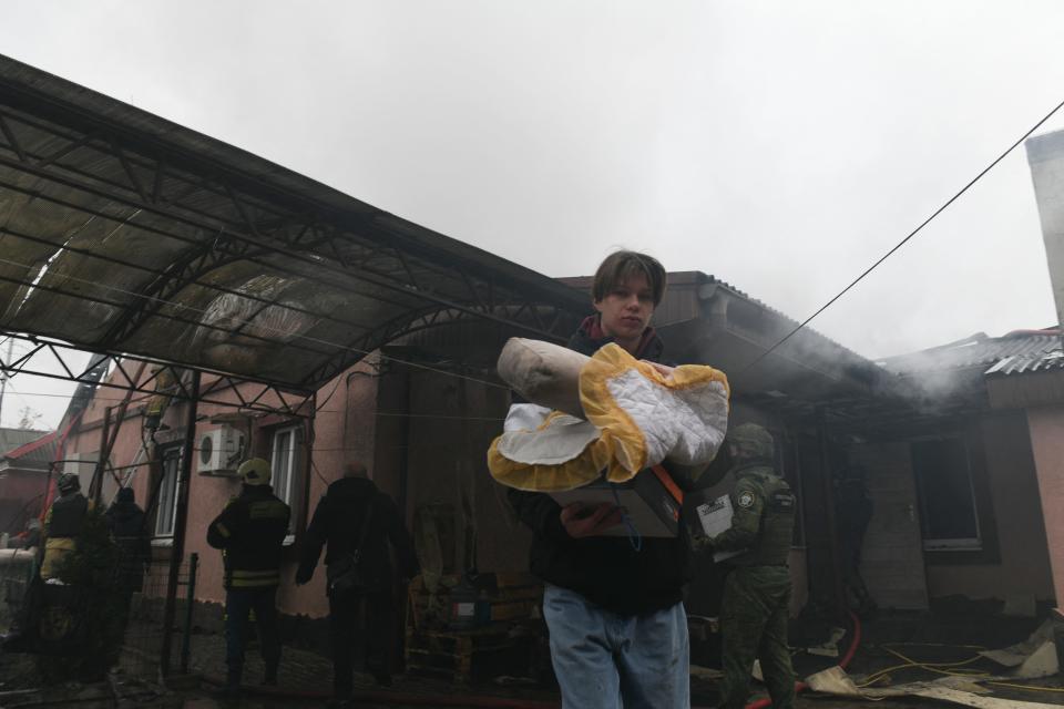 Residents and neighbors carry belongings out of a house hit by recent shelling in Donetsk, Russian-controlled Ukraine, on Nov. 30, 2023, amid the Russia-Ukraine conflict.