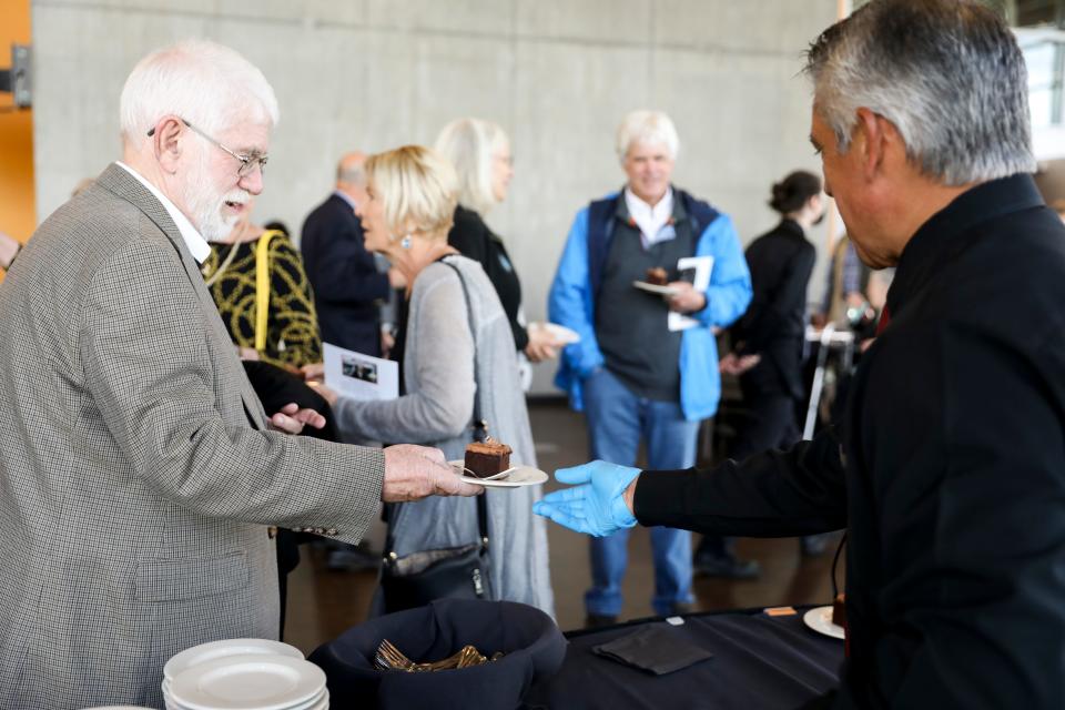 Mayor Chuck Bennett and other attendees eat chocolate cake in honor of Gerry Frank, a renowned businessman, author and philanthropist, during a celebration of life service at Salem Convention Center on Thursday.