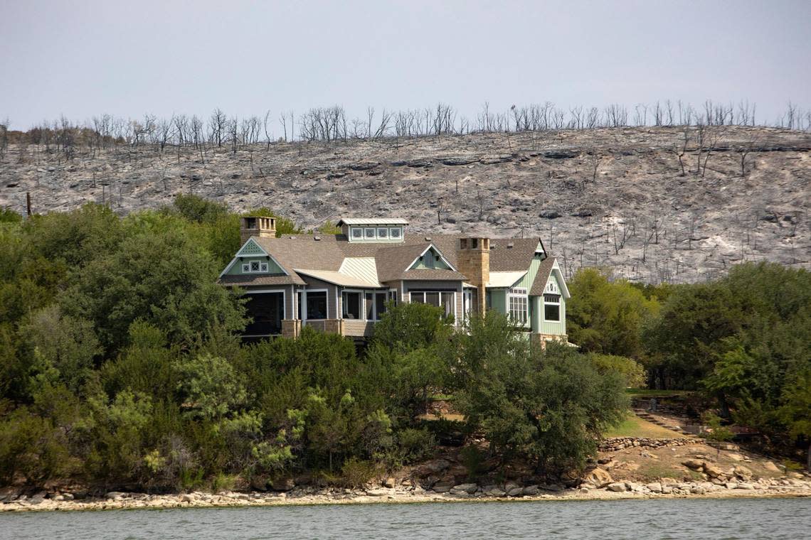 A house remains unaffected after a wildfire on the coast of Possum Kingdom Lake in Graford, Texas, on Wednesday, July 20, 2022.