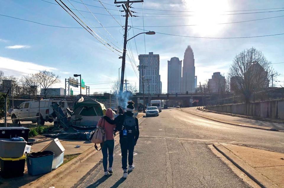 A couple walk up the street near a now-closed homeless encampment in Charlotte, on Feb. 18, 2021.