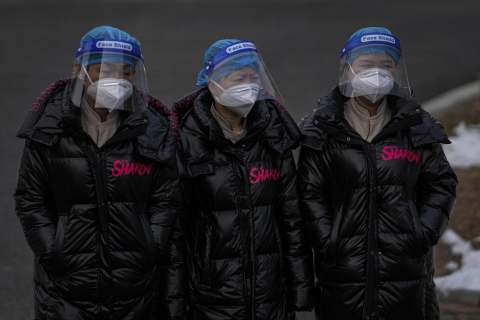 Workers wearing face shields and masks to help protect from the coronavirus head to a hotel used for people to stay during a period of health quarantine Sunday, March 20, 2022, in the Yanqing district of Beijing. (AP Photo/Andy Wong)