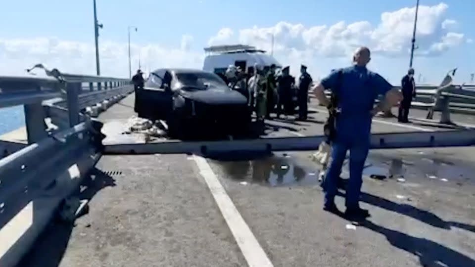 Russian investigators gather near a destroyed car at the damaged section of the bridge on July 17, 2023. - Investigative Committee of Russia/Handout/Reuters