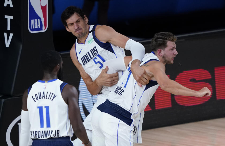 Dallas Mavericks' Luka Doncic (77) is restrained by his teammate Dallas Mavericks' Boban Marjanovic, right, after being fouled by Los Angeles Clippers' Marcus Morris Sr. during the first half of an NBA first round playoff game Sunday, Aug. 30, 2020, in Lake Buena Vista, Fla. (AP Photo/Ashley Landis)