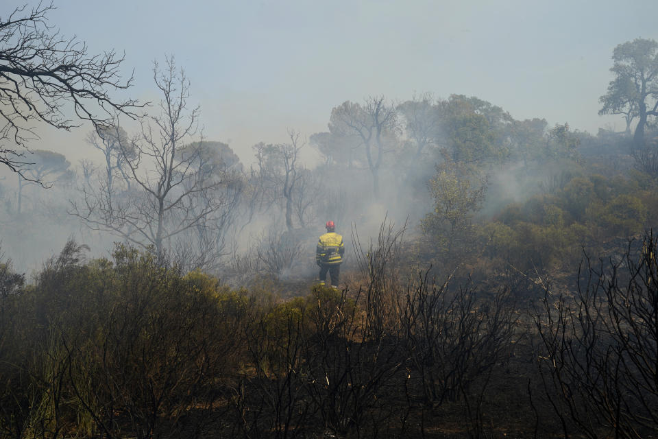 A fireman stands in a devastated landscape after a fire broke out in a forest near Le Luc, southern France, Tuesday, Aug. 17, 2021. Thousands of people were evacuated from homes and vacation spots near the French Riviera as firefighters battled a fire racing through surrounding forests Tuesday, the latest of several wildfires that have swept the Mediterranean region.(AP Photo/Daniel Cole)