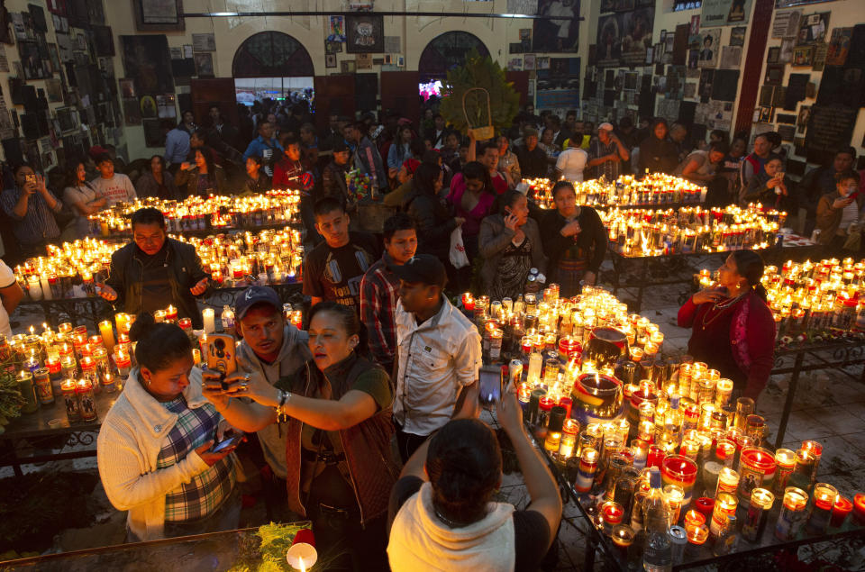 In this Oct. 28, 2019 photo, people take selfies inside the church dedicated to folk saint Maximon on his feast day in San Andres Itzapa, Guatemala. Sometimes called San Simon, Maximon is a an indigenous character worshipped by Mayans in the highlands of Western Guatemala. He is portrayed as a human character who likes alcohol and cigarettes, and includes the homeless and prostitutes as some of his loyal followers. (AP Photo/Moises Castillo)