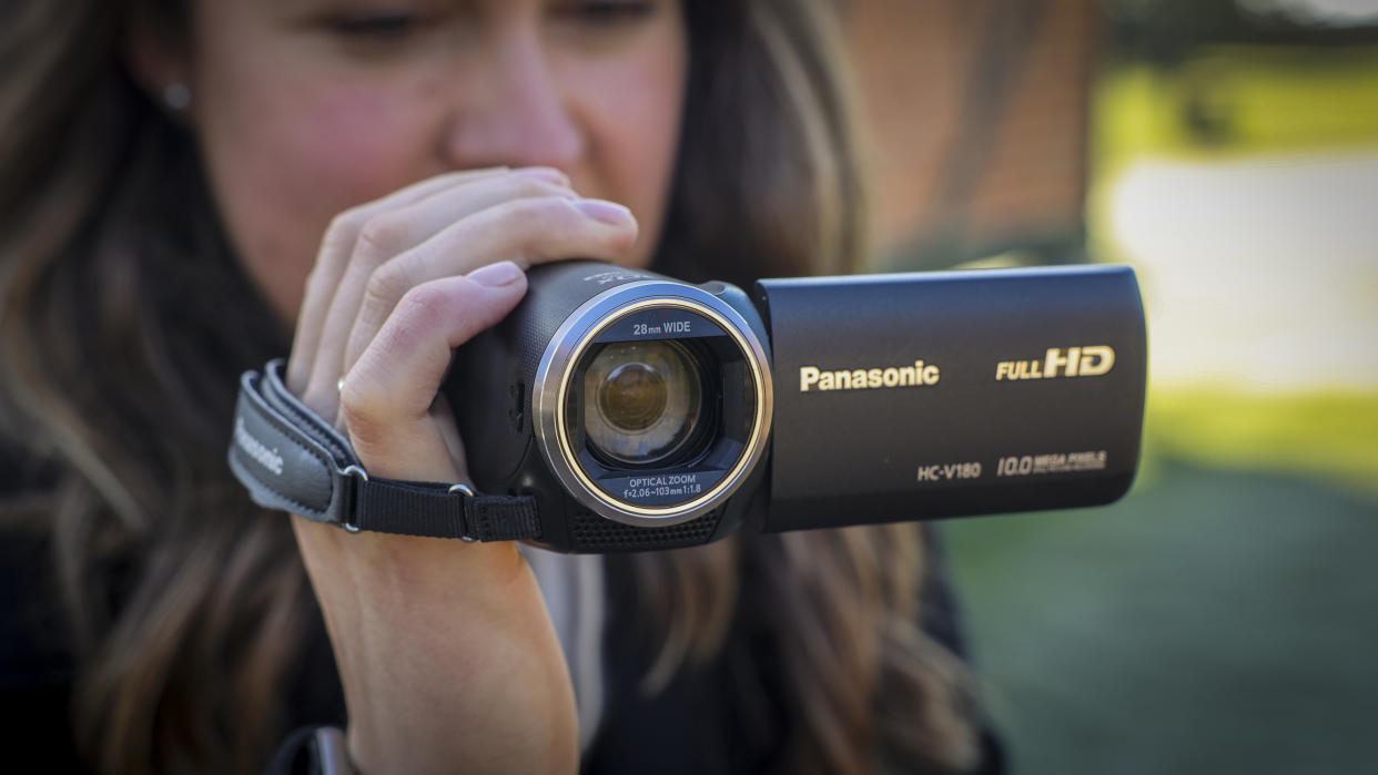  The Panasonic HC-V180 camcorder being held by a young woman. 