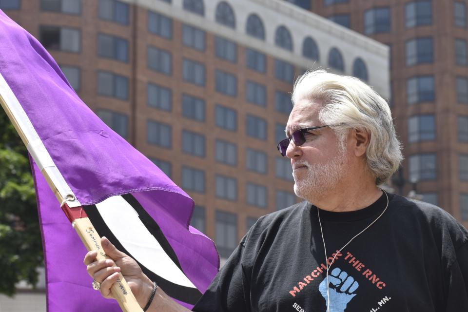 Brian Verdeen of the Milwaukee Alliance Against Racist and Political Repression holds a Peace Sign Flag, a symbol to represent peace that originates from the British anti-nuclear movement in 1958.